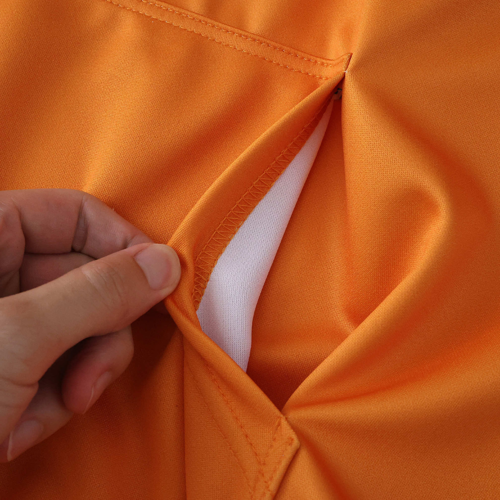 Orange motorsport jacket lining detail, showing inner white fabric and stitching from revnhaus