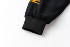 Black racing jacket sleeve with gold embroidered logo and ribbed cuff from revnhaus