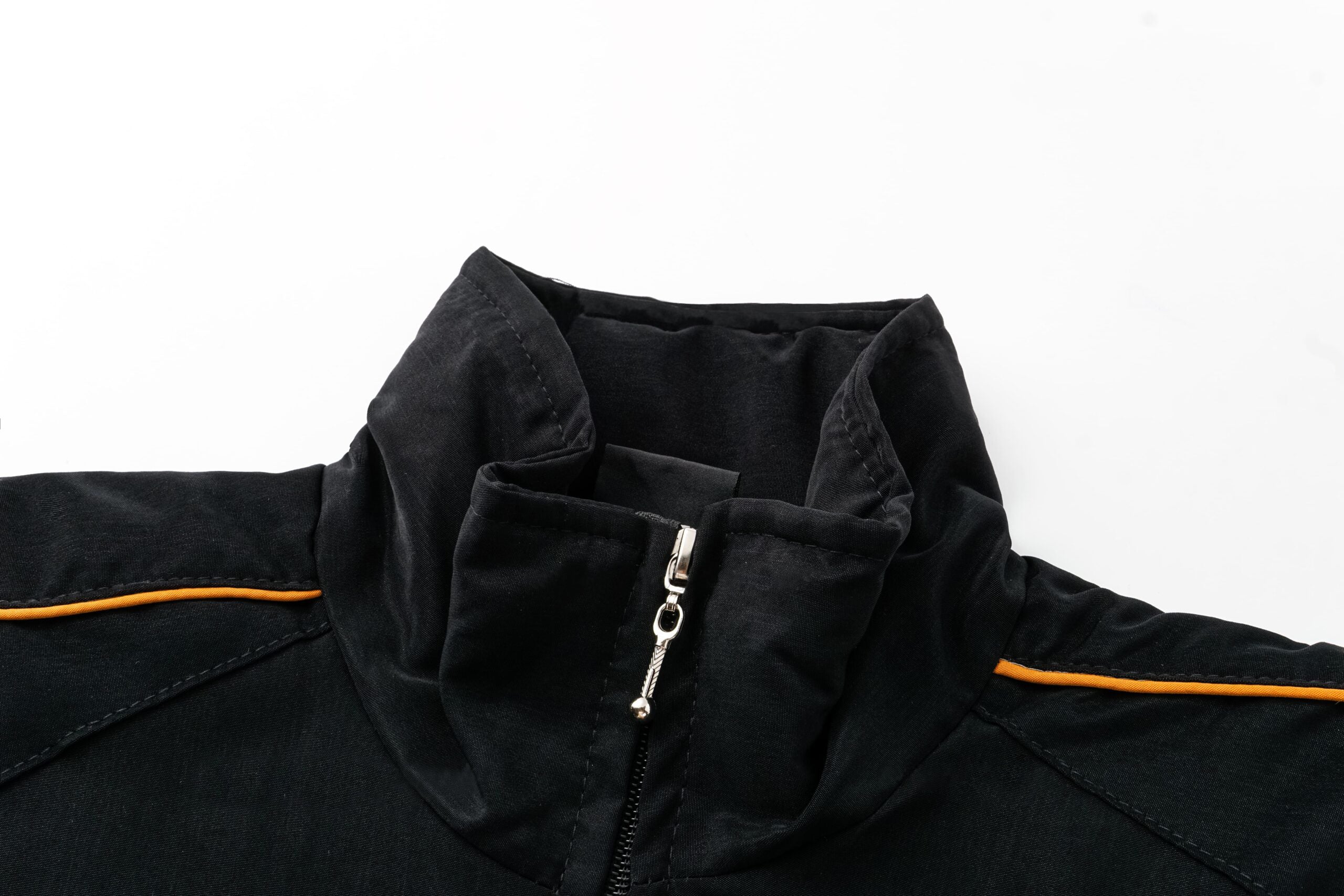 Black motorsport racing jacket with orange trim and zipper detail from revnhaus