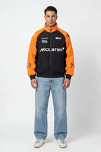 Man wearing McLaren racing jacket with orange sleeves and sponsor logos from revnhaus
