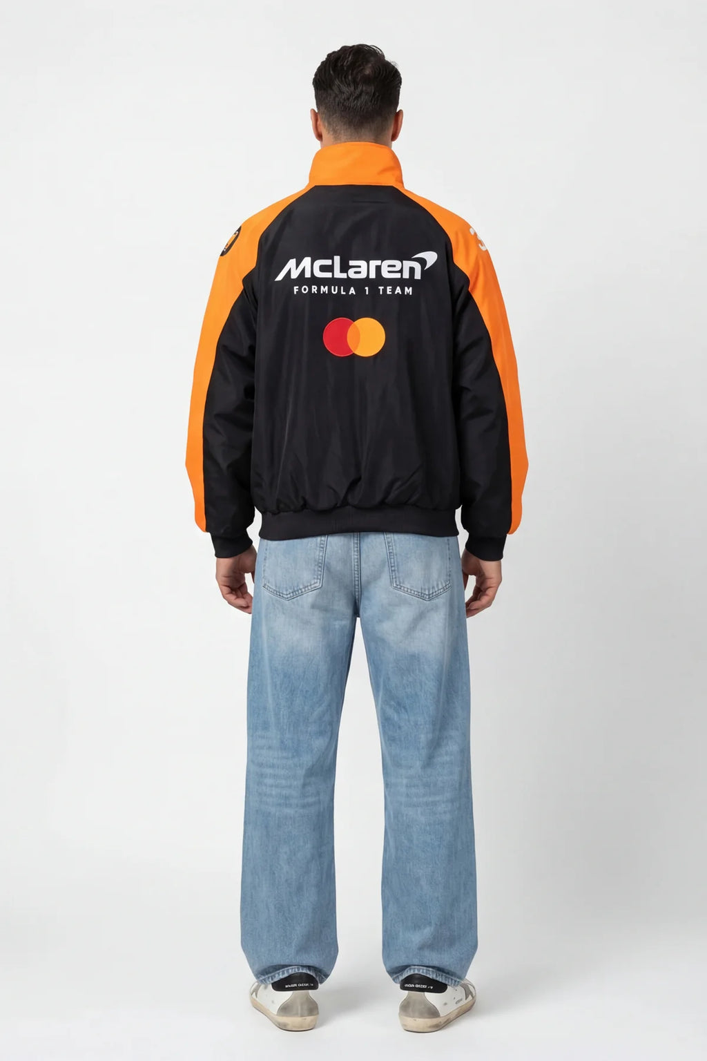 Black and orange McLaren Formula 1 Team bomber jacket with Mastercard logo, worn with jeans from revnhaus