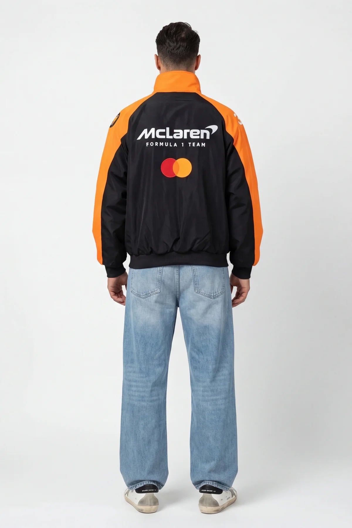 Black and orange McLaren Formula 1 Team bomber jacket with Mastercard logo, worn with jeans from revnhaus