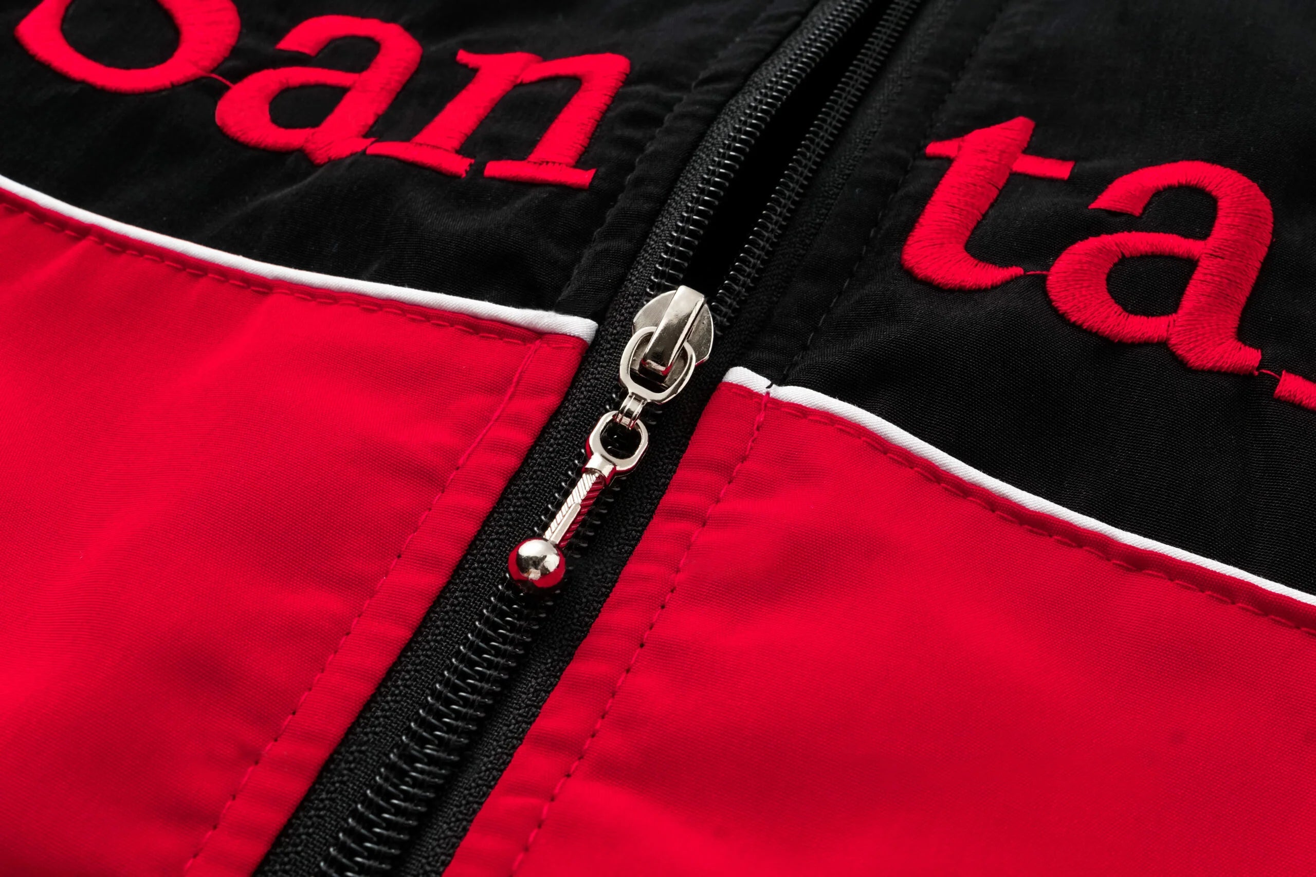 Red and black racing jacket with embroidered logo and zipper detail from revnhaus