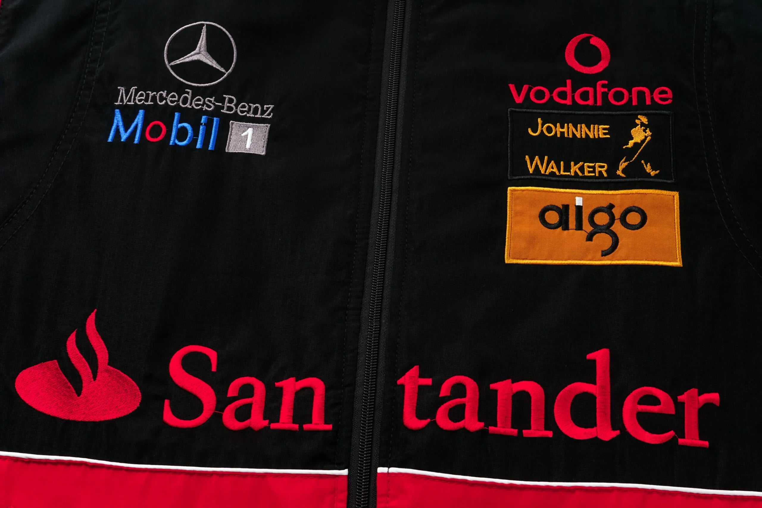 Black F1 racing jacket with Mercedes-Benz, Mobil 1, Vodafone, Santander logos from revnhaus