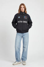 Woman wearing black BMW M Power racing jacket with Petronas logo, styled with light jeans from revnhaus