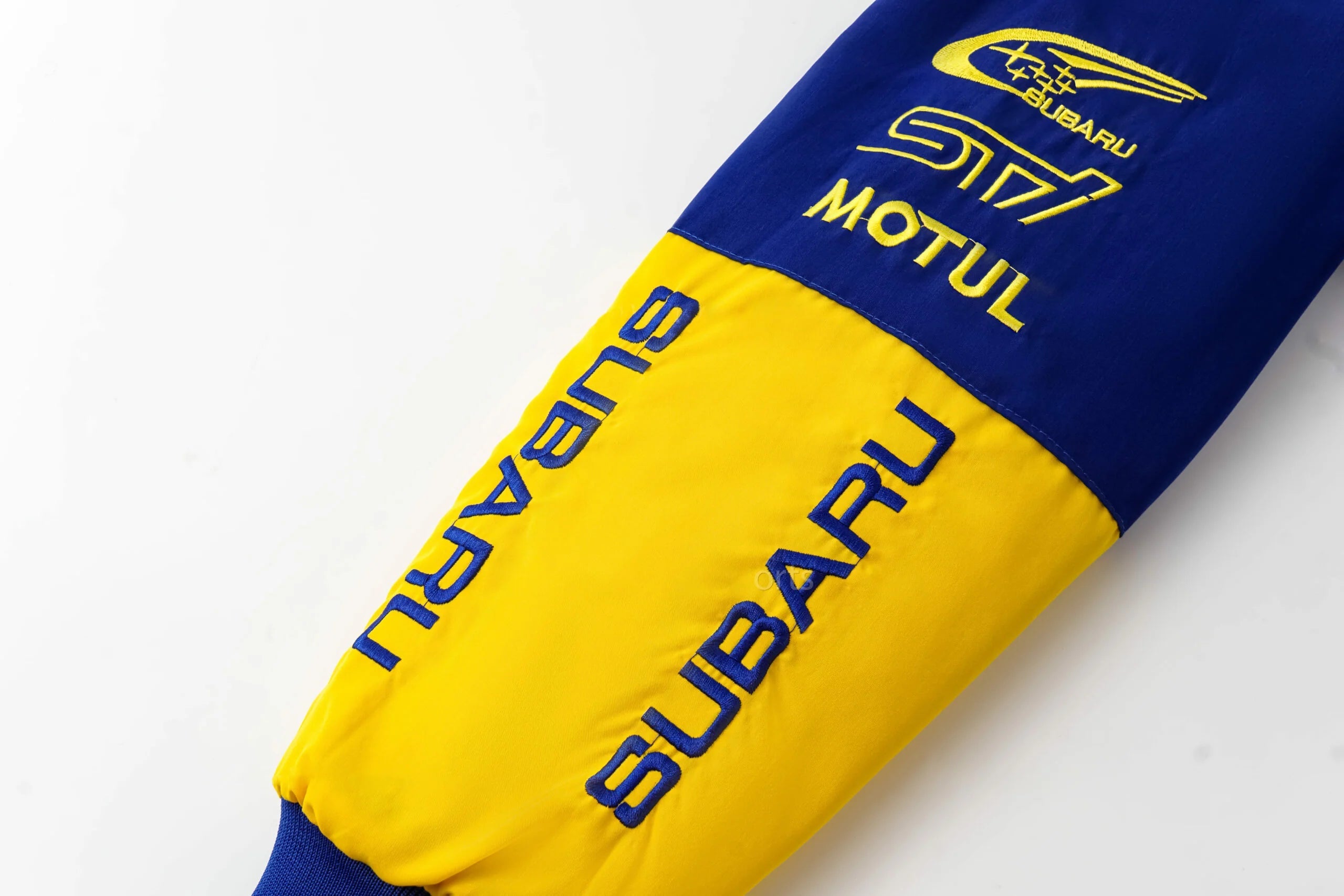 Blue and yellow Subaru racing jacket sleeve with Motul logo embroidery from revnhaus