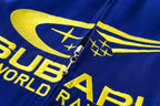 Blue racing jacket with yellow embroidered 'Club World Rally' logo and zipper detail from revnhaus