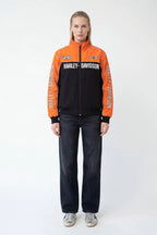 Orange and black Harley-Davidson racing jacket with bold branding, styled with jeans and sneakers from revnhaus