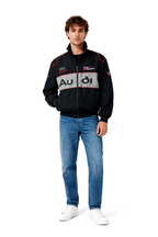 Audi Sport racing jacket with bold logo stripe, black design, red trim, worn with jeans and white sneakers from revnhaus
