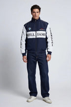Men's navy and white Williams F1 racing jacket with BMW logo, styled with jeans and sneakers from revnhaus