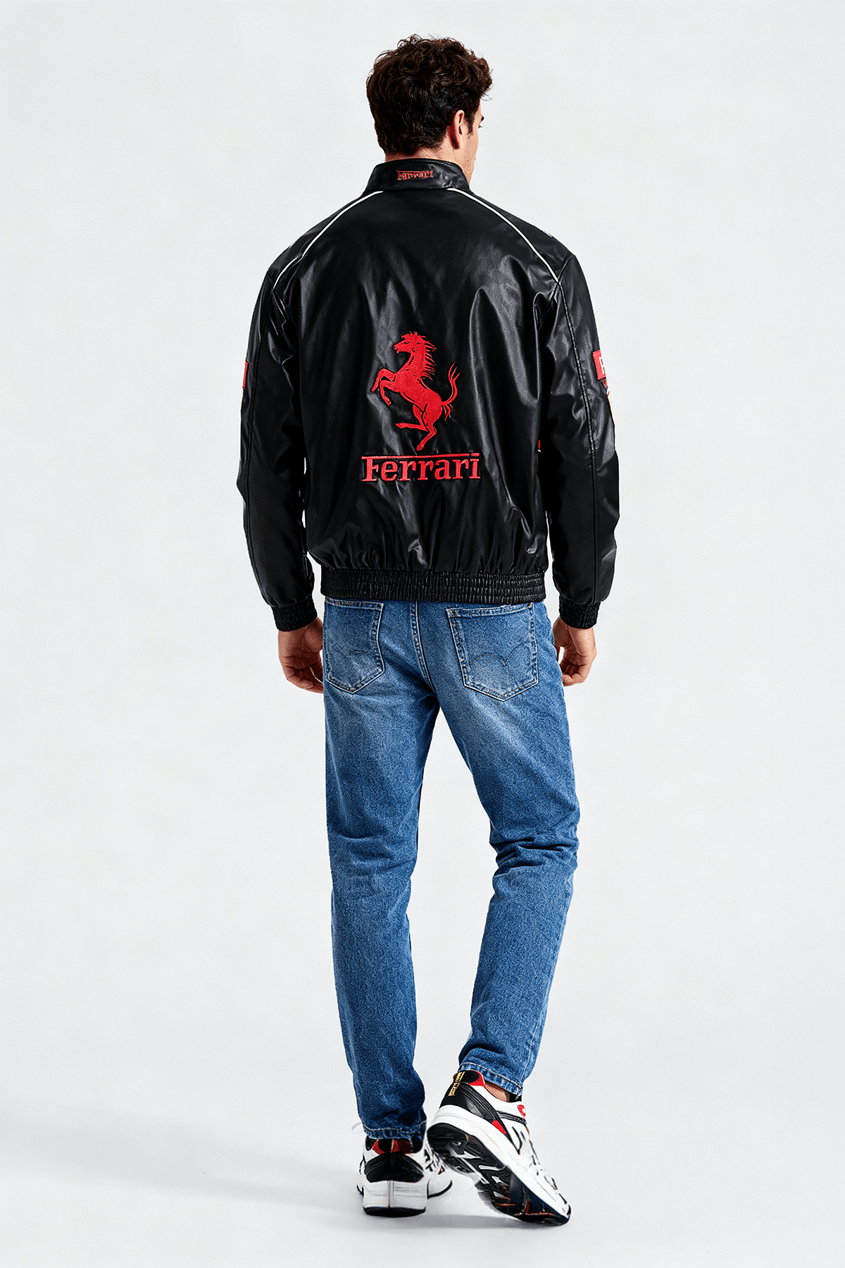 Black Ferrari racing jacket with red prancing horse logo, worn with jeans and sneakers from revnhaus