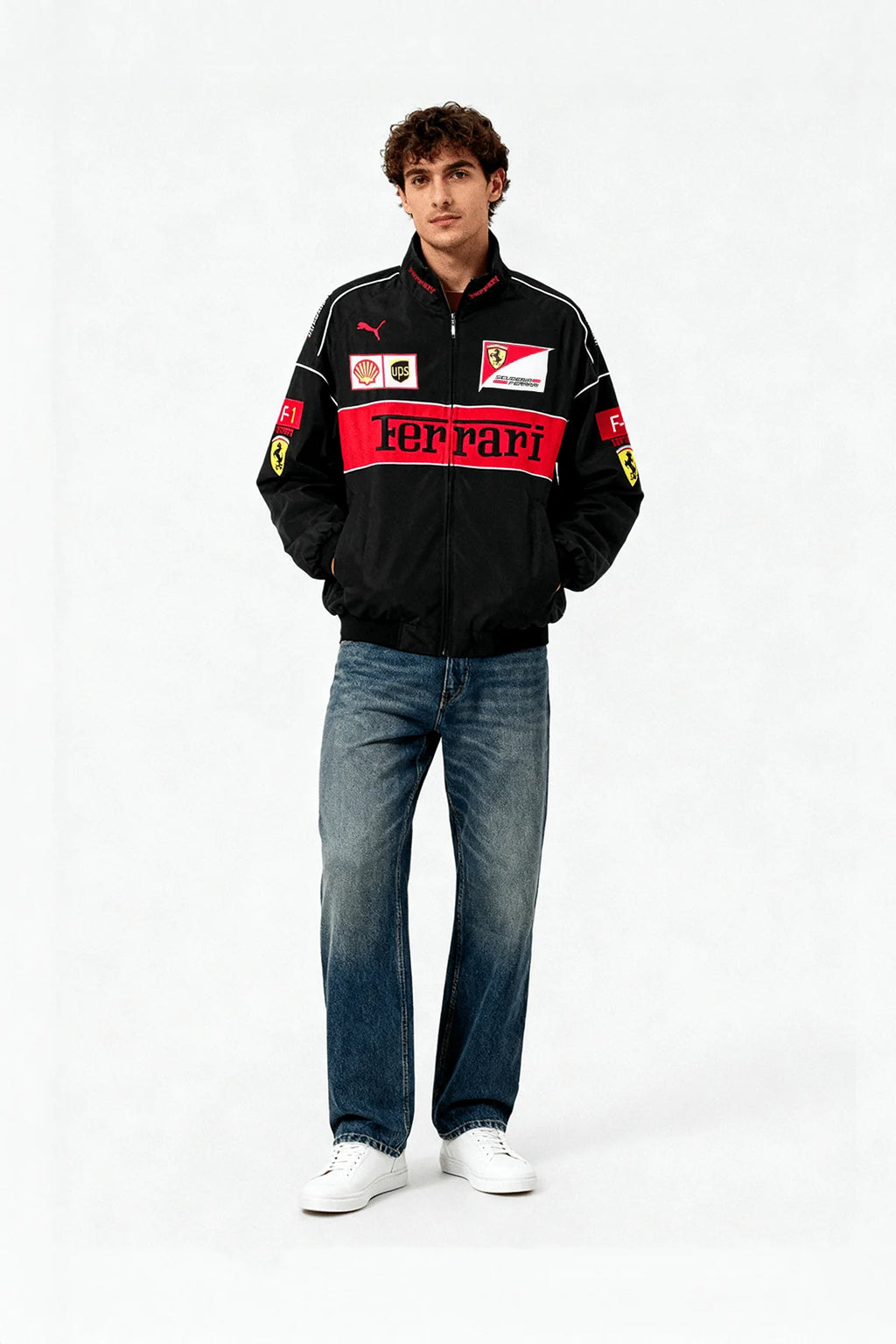 Man wearing black Ferrari racing jacket with red accents and logos, paired with jeans and white sneakers from revnhaus