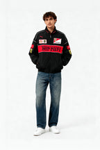 Man wearing black Ferrari racing jacket with red accents and logos, paired with jeans and white sneakers from revnhaus