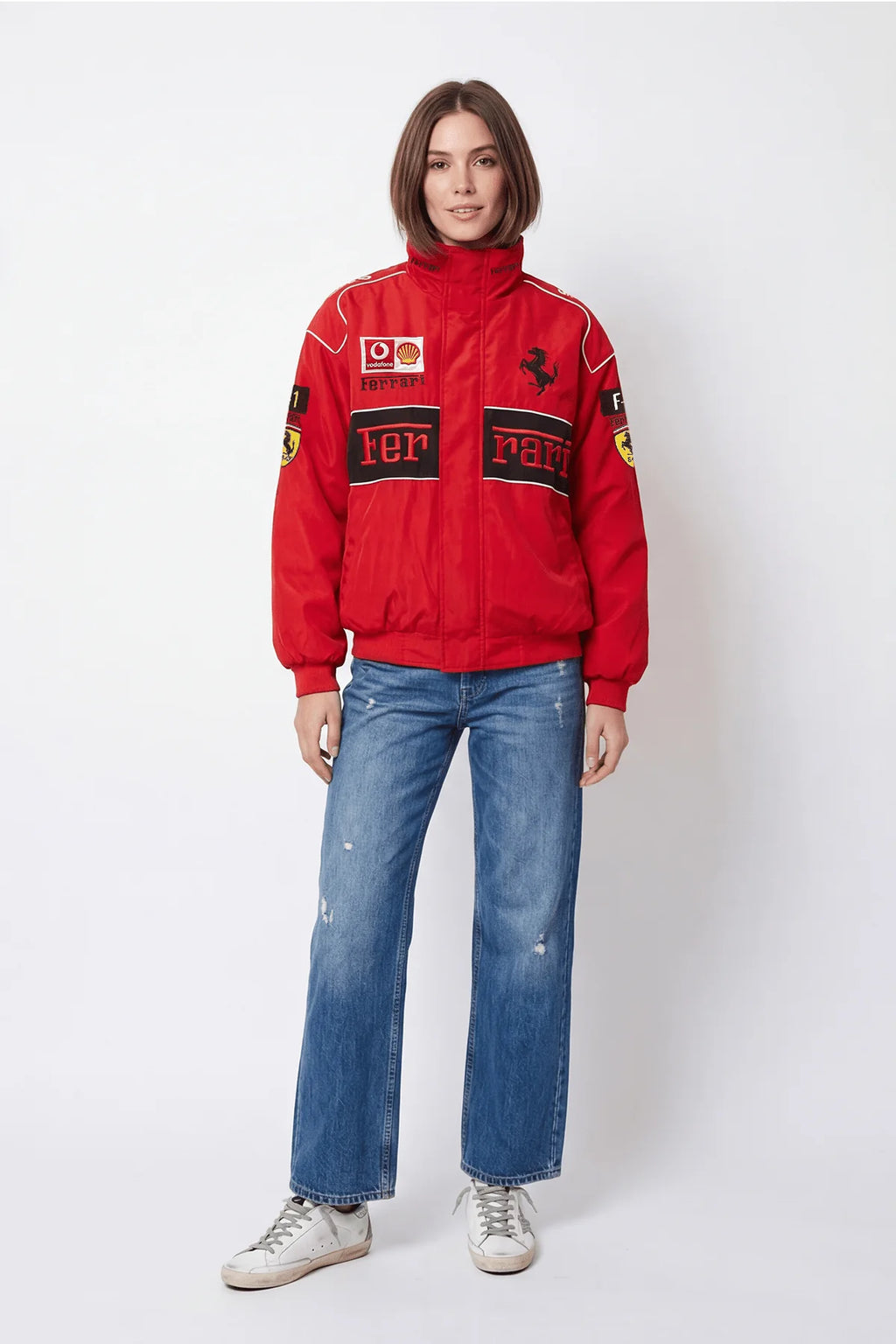 Red Ferrari racing jacket with logos, paired with distressed jeans and white sneakers from revnhaus
