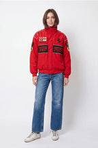 Red Ferrari racing jacket with logos, paired with distressed jeans and white sneakers from revnhaus