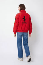 Red Ferrari racing jacket with prancing horse logo, worn with blue jeans from revnhaus