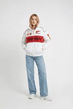 White Ferrari racing jacket with red stripe and sponsor logos, styled with jeans and sneakers from revnhaus