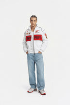 Man wearing white Ferrari racing jacket with red accents and jeans, from revnhaus
