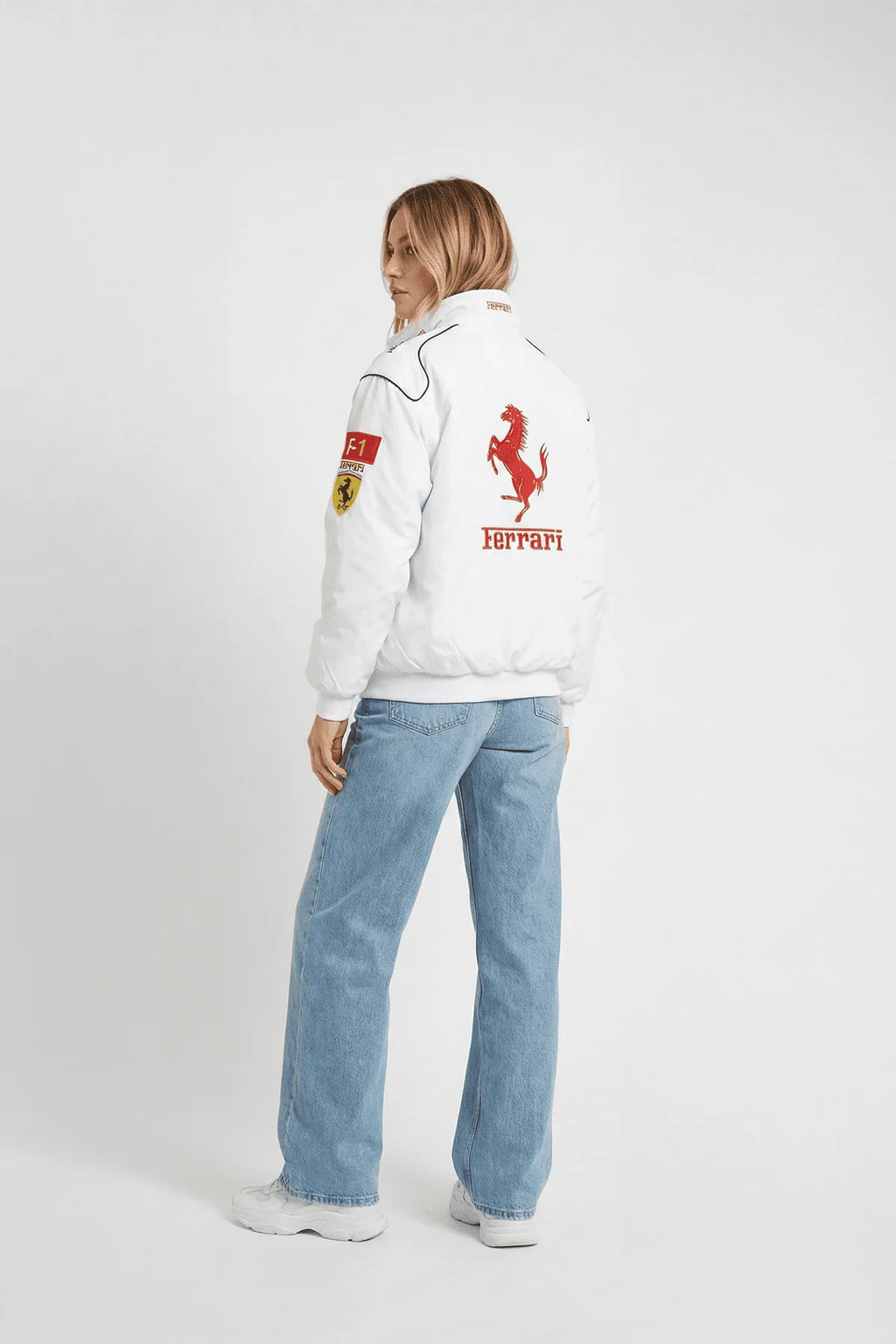 White Ferrari racing jacket with red prancing horse logo, worn with blue jeans from revnhaus