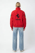 Red Ferrari racing bomber jacket with prancing horse logo, worn by woman in jeans from revnhaus