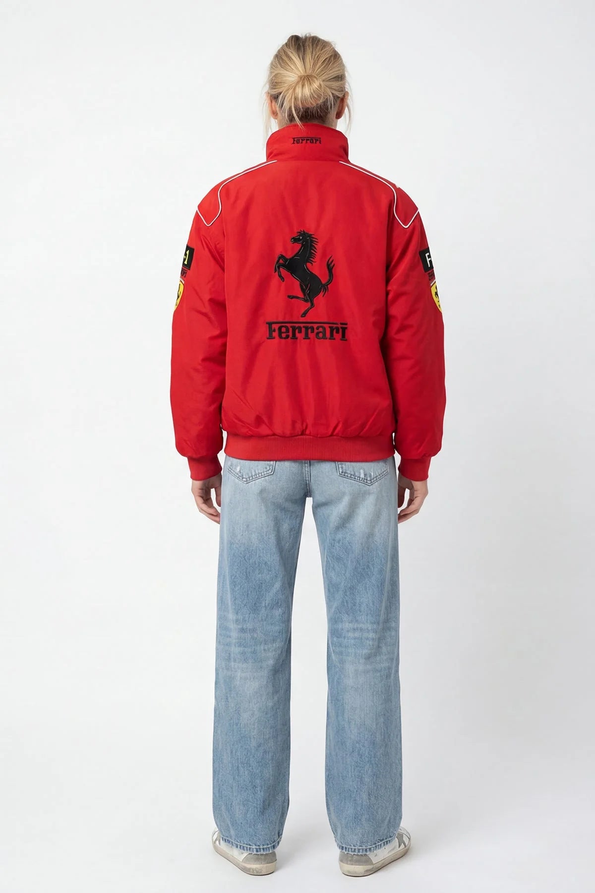 Red Ferrari racing bomber jacket with prancing horse logo, worn by woman in jeans from revnhaus