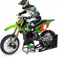 Green RC motocross bike with rider in Fox gear on stand from revnhaus
