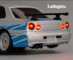 Silver and blue die-cast drift car with glowing taillights and rear spoiler from revnhaus