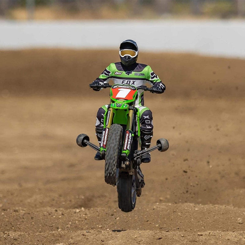 RC drift bike with rider in green Fox gear mid-air on dirt track from revnhaus