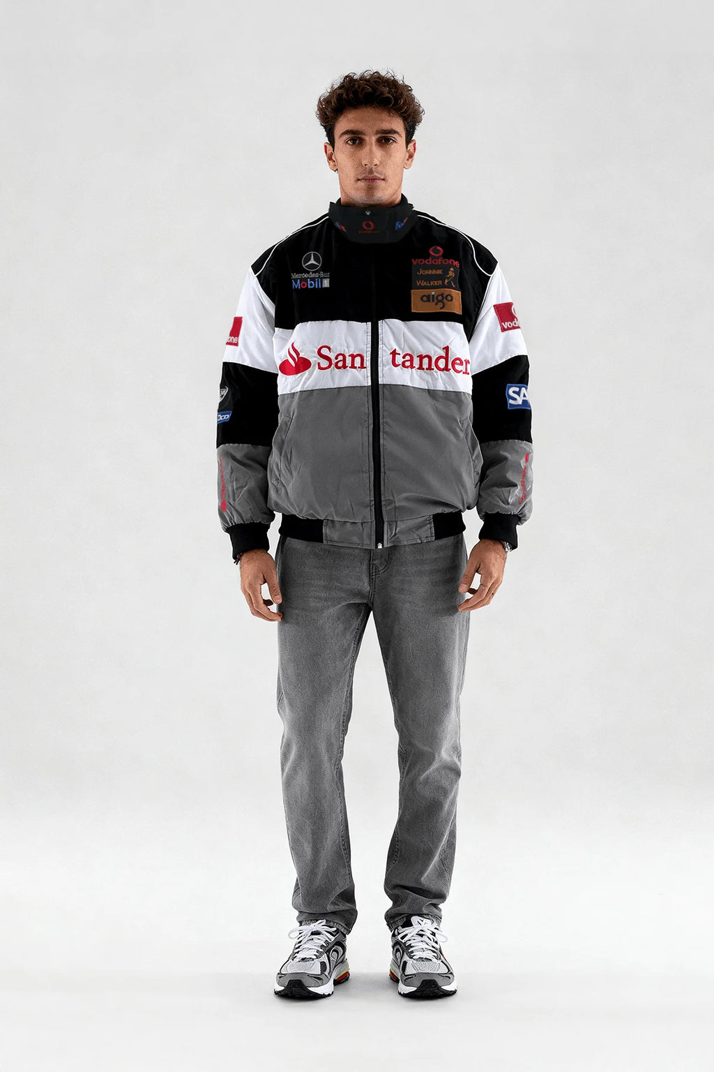Racing-inspired puffer jacket with sponsor logos, styled with gray jeans and sneakers from revnhaus