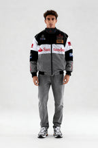 Racing-inspired puffer jacket with sponsor logos, styled with gray jeans and sneakers from revnhaus