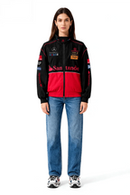 Black and red racing-style jacket with sponsor logos, worn with blue jeans and sneakers from revnhaus