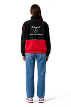 Black and red McLaren Mercedes-Benz racing jacket with logo, worn with jeans from revnhaus