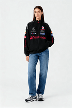 Black racing-style jacket with sponsor logos, paired with blue jeans and sneakers from revnhaus