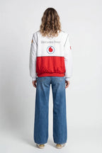 White and red racing bomber jacket with Mercedes-Benz and Vodafone logos, worn with wide-leg jeans from revnhaus