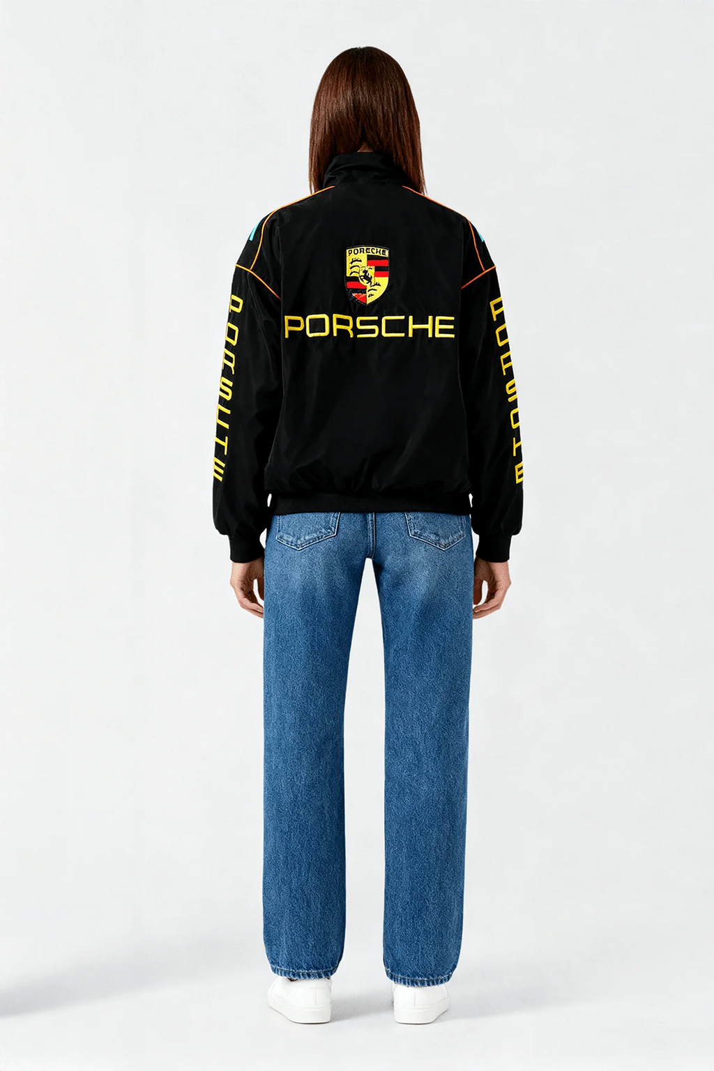 Black Porsche racing jacket with yellow logo and sleeve text, worn with blue jeans from revnhaus