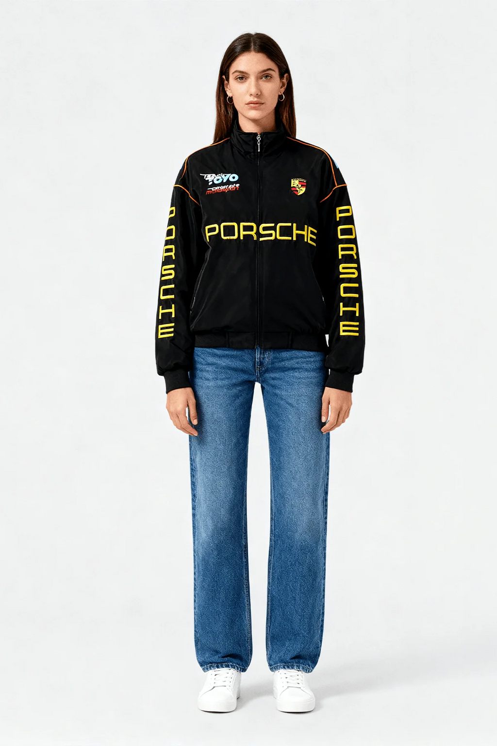 Black Porsche racing jacket with yellow lettering and logos, styled with jeans and sneakers from revnhaus