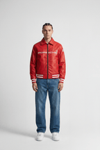 Red Porsche racing jacket with white stripes, worn with jeans and sneakers from revnhaus