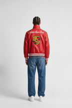 Red Porsche varsity jacket with Aime Leon Dore branding, worn with jeans from revnhaus