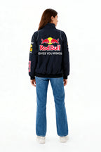 Red Bull racing jacket with 'Gives You Wings' logo on back, worn by woman in jeans from revnhaus