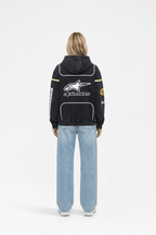 Black Alpinestars racing hoodie with white star logo and yellow stripes, worn with blue jeans from revnhaus