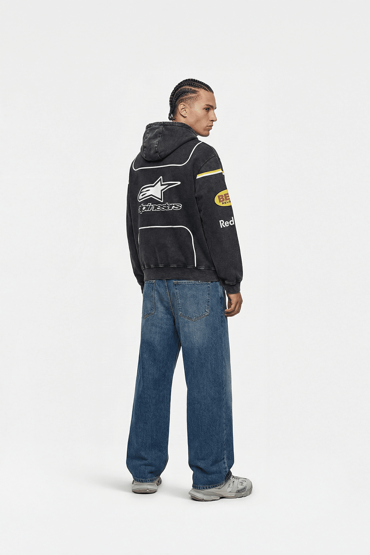 Black Alpinestars racing hoodie with sponsor logos, worn with jeans and sneakers from revnhaus