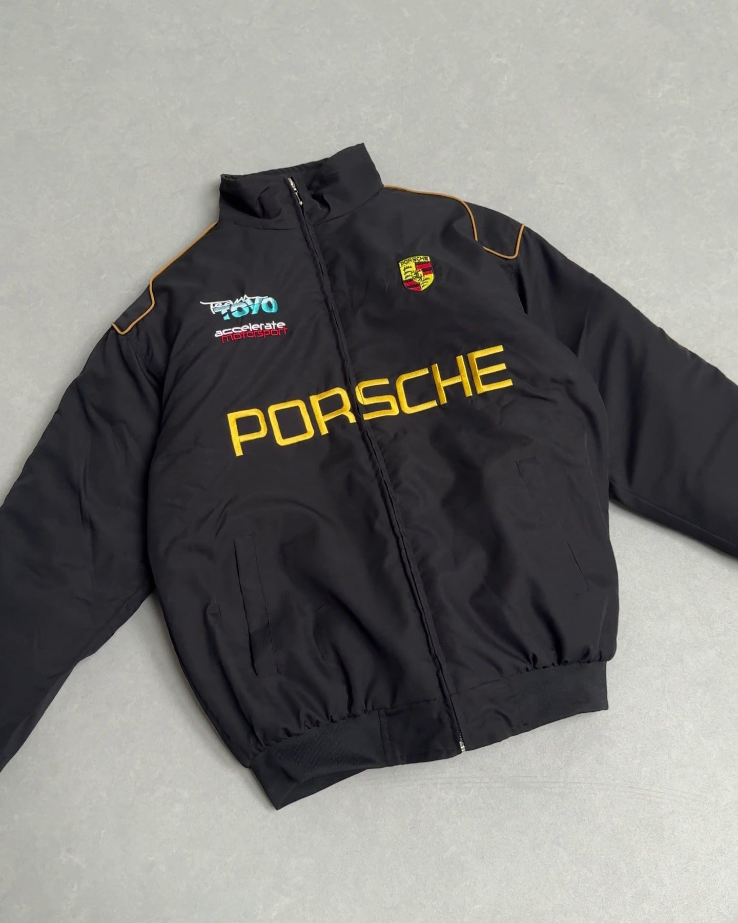 Black Porsche motorsport jacket with yellow logo and Team TOYO patch from revnhaus