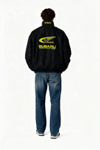 Black Subaru World Rally Team jacket with yellow logo, worn by model from behind, from revnhaus