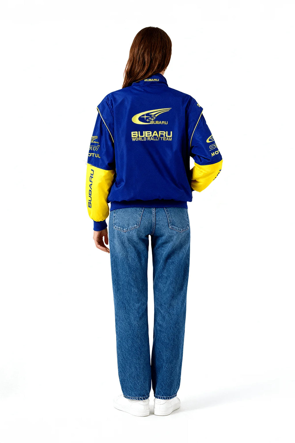 Blue and yellow Subaru World Rally Team jacket with racing logos, worn with jeans from revnhaus