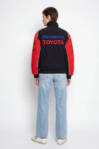 Black and red Panasonic Toyota racing jacket with bold logos, worn with light jeans from revnhaus