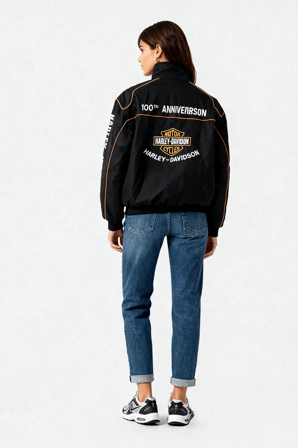 Black Harley-Davidson 100th Anniversary racing jacket with orange trim, worn by woman in jeans from revnhaus