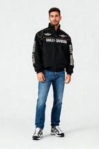 Black Harley-Davidson racing jacket with bold branding and orange trim, worn with jeans and sneakers from revnhaus